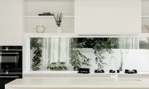A modern kitchen with white cabinets and countertops and a round dining table with wooden chairs