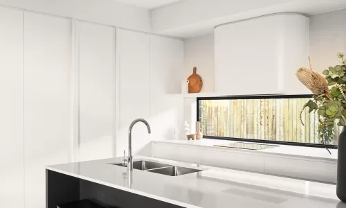 Modern kitchen with white cabinets, black stools, a white island, and a sink under a large window