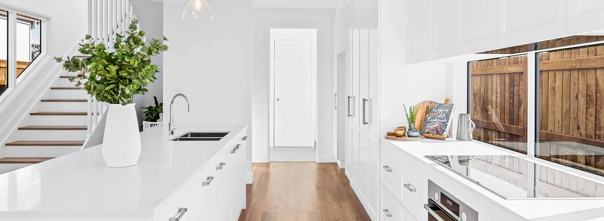 White kitchen with waterfall island, floor-to-ceiling cabinetry and a window splashback by Weston Kitchens