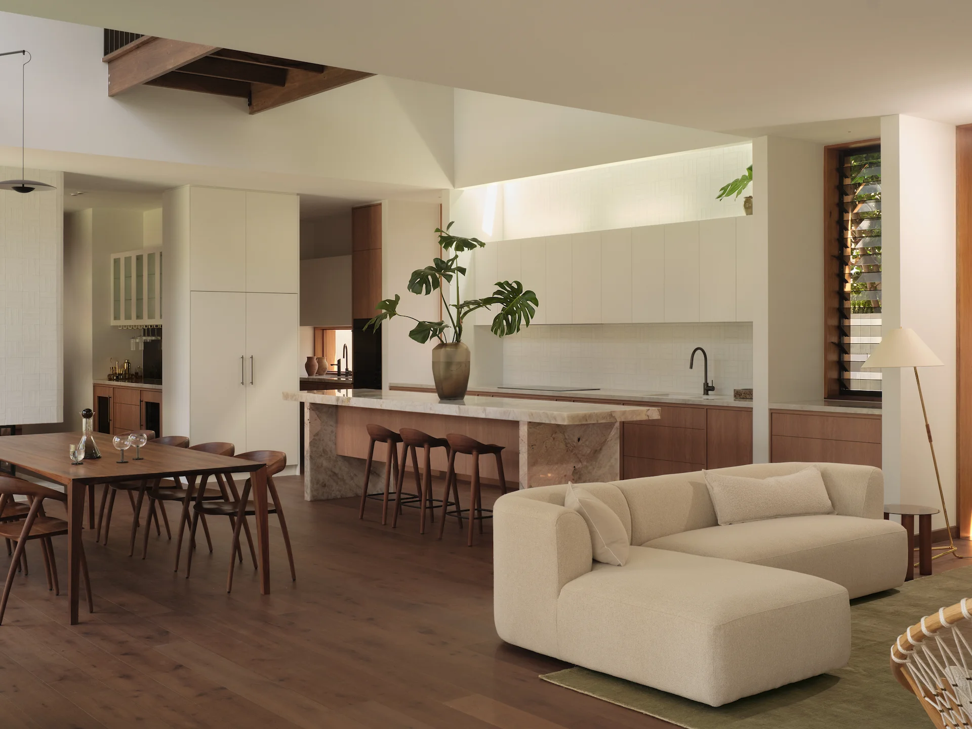 Modern open-concept interior featuring a dining table, kitchen island, and cream sofa.