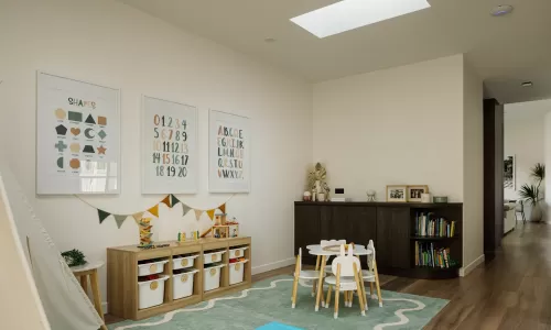 Bright playroom with kids’ table, toy storage, educational posters, and wood flooring.