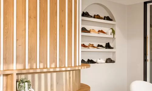 Curved wood reception and arched shoe display wall.