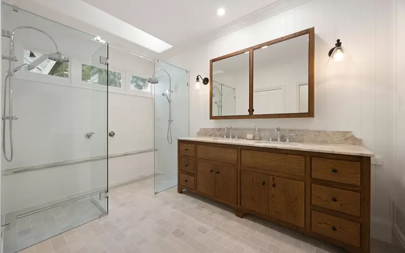 Modern bathroom with wood vanity, glass shower.