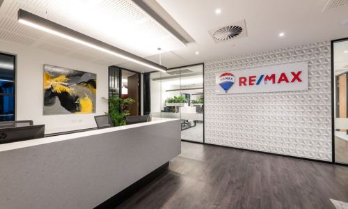 Remax white Front Desk with Remax logo on the wall