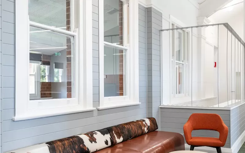 Inviting lounge nook with a brown leather bench, cowhide bolster cushion, orange chair, and round table.