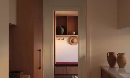 Hallway view into a mudroom with a straw hat, shoes, and a bench, flanked by kitchen counters.