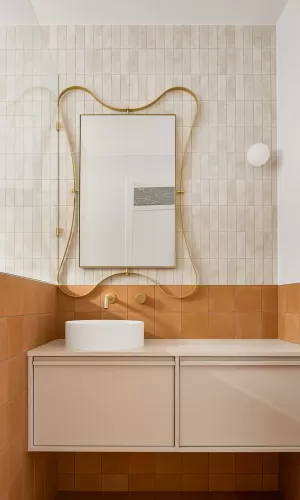 A modern bathroom with a gold-framed mirror, and white and brown tiles