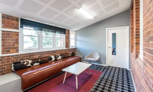 Cozy lounge with a brown leather bench, cowhide bolster, modern coffee table, and gray accent chair.