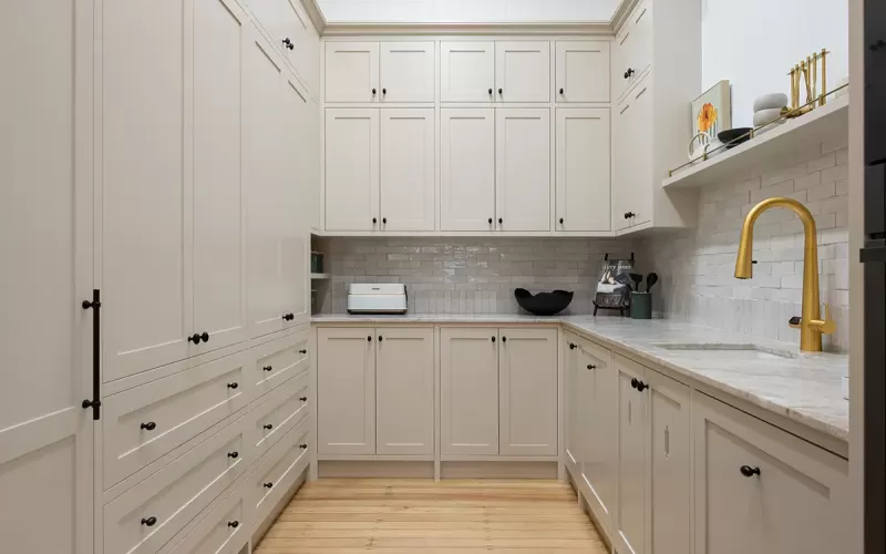 White butler's pantry with gold faucet.