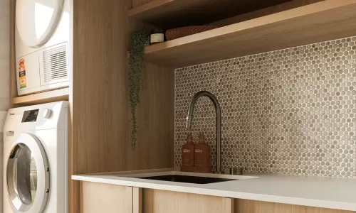 Modern laundry room with wooden cabinets, stacked washer and dryer, sink, and penny tile backsplash