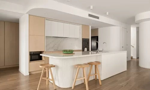 Curved white island in bright wood-accented kitchen