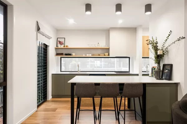 Modern kitchen with wooden floor, white walls, and grey cabinets