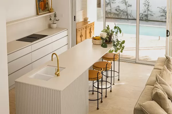 A modern kitchen with overlooking a pool through glass sliding doors