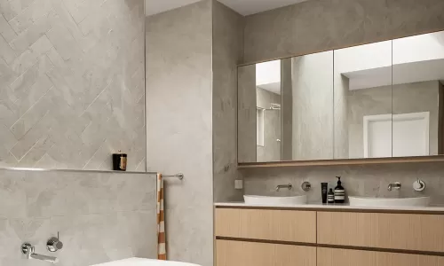 Freestanding tub beside wood vanity and wall mirror