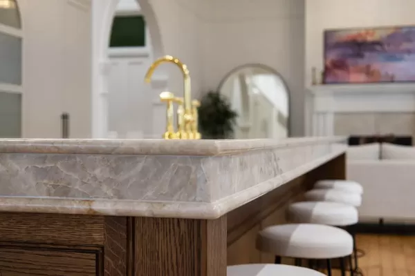 Kitchen island with marble countertop and gold faucet.