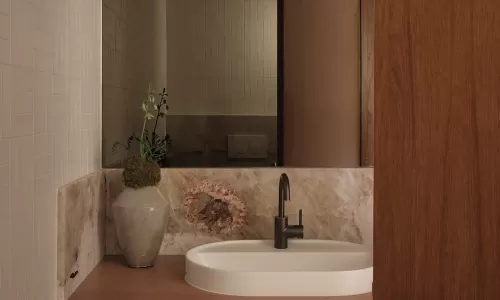 Powder room with a floating wood vanity, oval undermount sink, marble backsplash, and large mirror.
