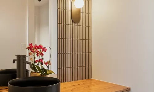 Modern bathroom interior with a wooden vanity top and a small potted orchid on the counter