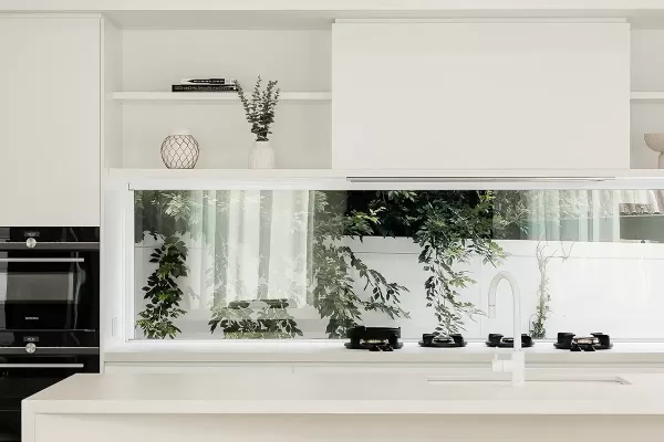 A modern kitchen with white cabinets and countertops and a round dining table with wooden chairs