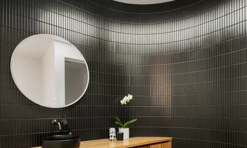 A modern bathroom with a round mirror and skylight