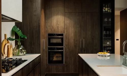 Contemporary kitchen with dark wood cabinets, skylight, built-in ovens, and island sink.