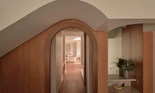 Wood-paneled hallway with an arched doorway leading to a bright, modern living space.