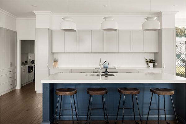 Modern white kitchen with navy blue island, wood accents, and minimalist design.