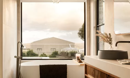 Modern bathroom with a freestanding tub, large window, wooden vanity, and pendant light