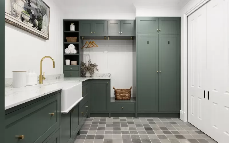 Laundry room with green cabinets and gray tile floor.