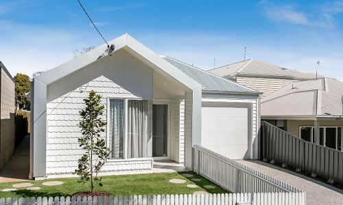 Front yard with a small tree and white fence