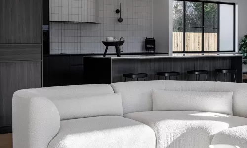 A modern living space featuring a cozy white boucle sofa, a minimalist black kitchen with dark cabinetry, and soft natural light filtering through large windows