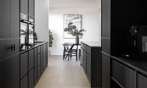 Sleek kitchen with black cabinetry, light wood flooring, skylights, and a modern dining area in view