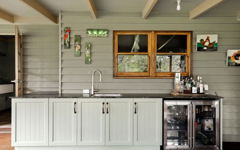 Outdoor kitchen sink with metal faucet and light green cabinet