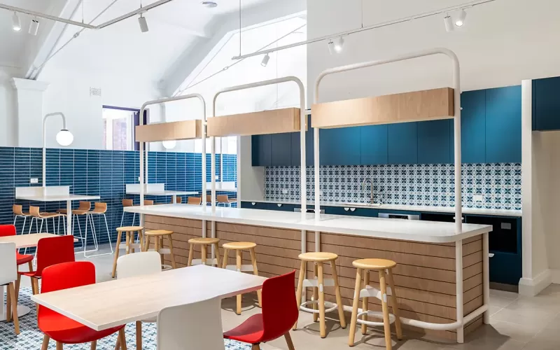 Modern kitchen and dining area with patterned tile backsplash, wood-accented island, and colorful seating.