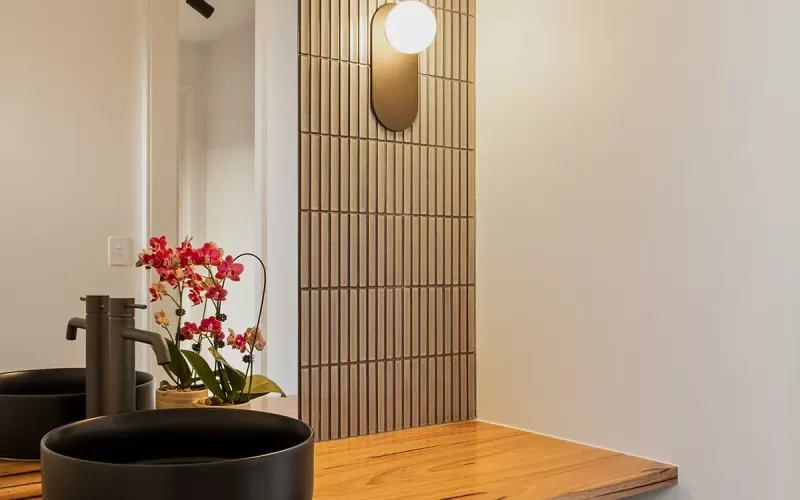 Modern bathroom with wooden vanity cabinet, and two circular mirrors with backlight