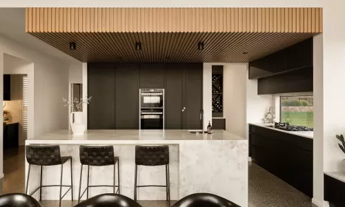 Modern kitchen with black cabinets, marble island, wooden ceiling, and bar stools. Minimalist design