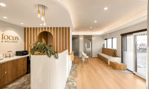 Clinic lobby with curved desk, wood bench, and plant.