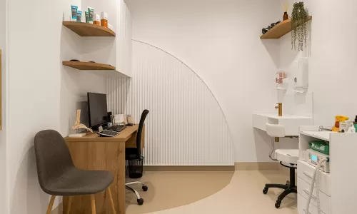 Podiatry exam room with desk, sink, and wall shelves.