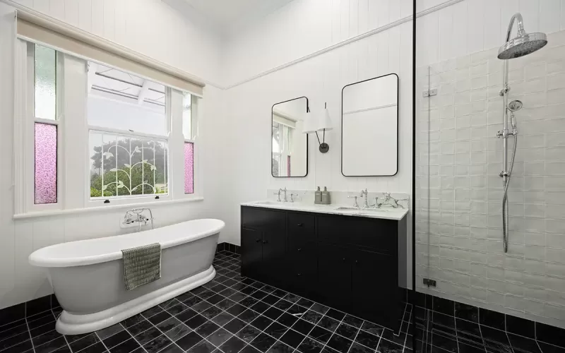 Elegant bathroom with clawfoot tub, black vanity, glass shower.
