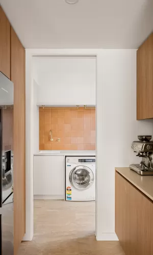 a modern laundry room with white walls and wooden cabinets