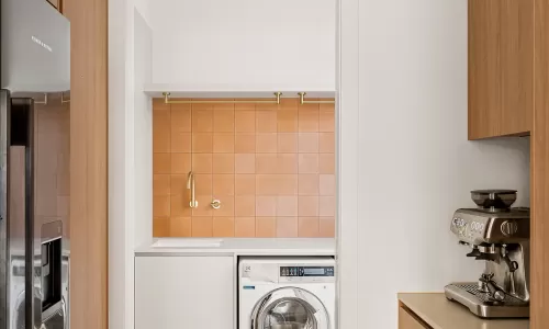 a modern laundry room with white walls and wooden cabinets