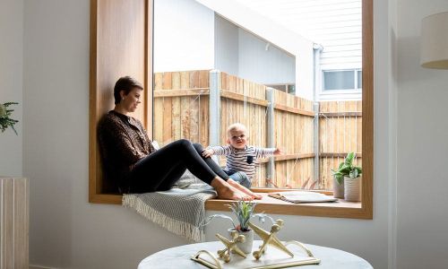 Girl and a kid sitting beside the glass window