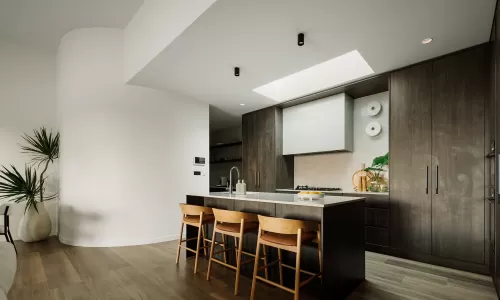 Sleek kitchen with wood cabinetry, island seating, skylight, and decorative green accents.