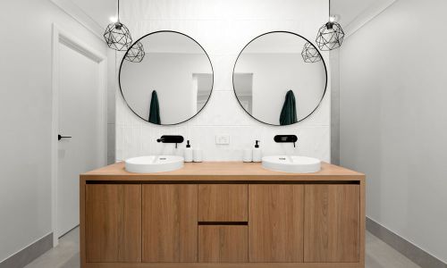 bathroom 2 white sink with black faucet and 2 circle mirrors with wooden cabinet