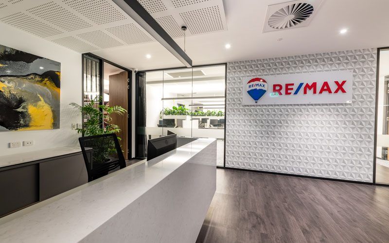 Remax white Front Desk with Remax logo on the wall